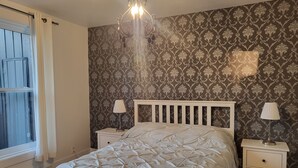 A bedroom with a bed, two bedside tables, a chandelier, and patterned wallpaper. - Superb apartment with terrace near metro rosemont (Montréal)