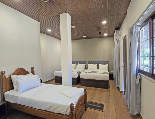 A hotel room with two beds, a wooden ceiling, and a window with curtains. - M Beach Resort (Colva)