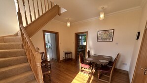 A spacious room with a wooden staircase, a dining area with a table and chairs, and a door leading to another room. - Shawsmill outside Hurlford (Hurlford)
