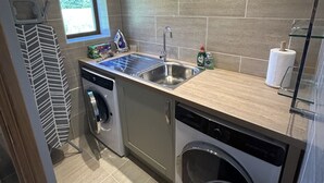 A compact kitchen with a built-in dishwasher, a sink, and a window providing natural light. - Shawsmill outside Hurlford (Hurlford)