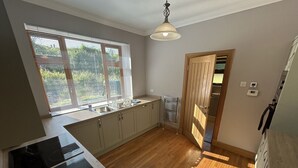 A kitchen with a large window, wooden flooring, and a built-in stove. - Shawsmill outside Hurlford (Hurlford)