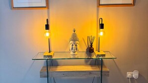 Een glazen bureau met twee zwarte lampen, een Boeddha-beeldje en een kleine vaas met rietstelen.