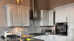 Een moderne keuken met witte kasten, een centraal eiland, roestvrijstalen apparatuur en een visgraat houten vloer.