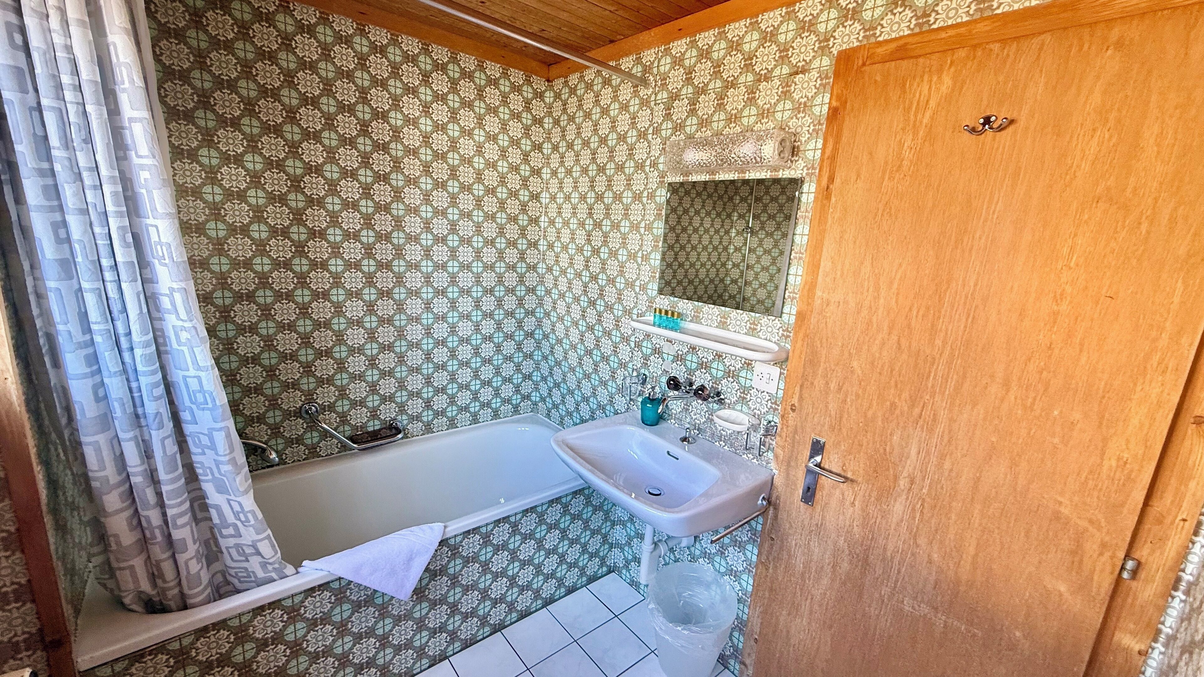 Une salle de bain avec une baignoire, un lavabo et des carreaux décorés.