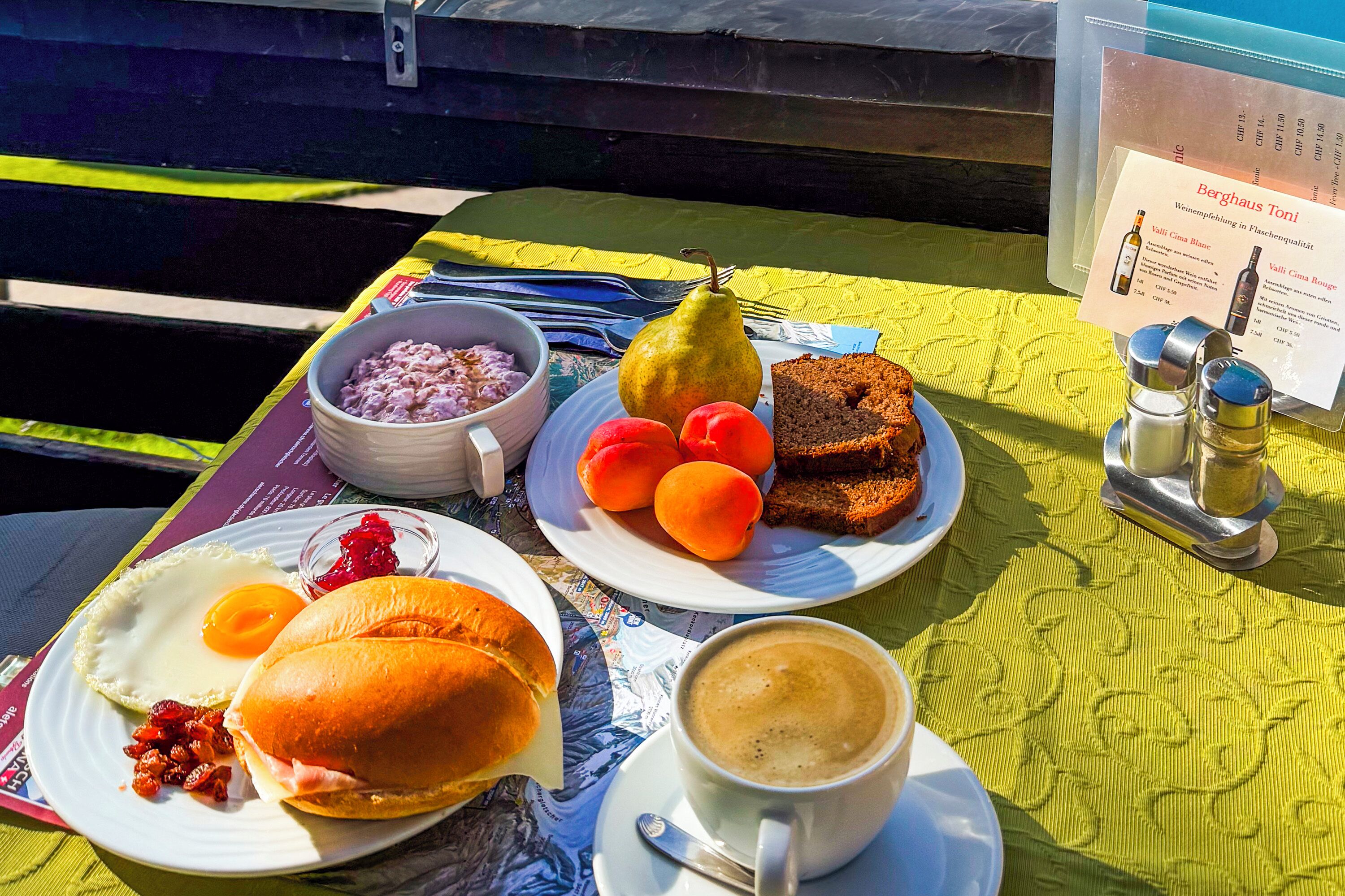 Une table de petit-déjeuner avec des œufs, des toasts, des fruits et une tasse de café.