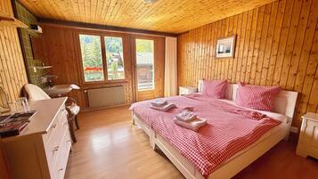 A wooden-paneled bedroom with a bed, bedside tables, and a window.