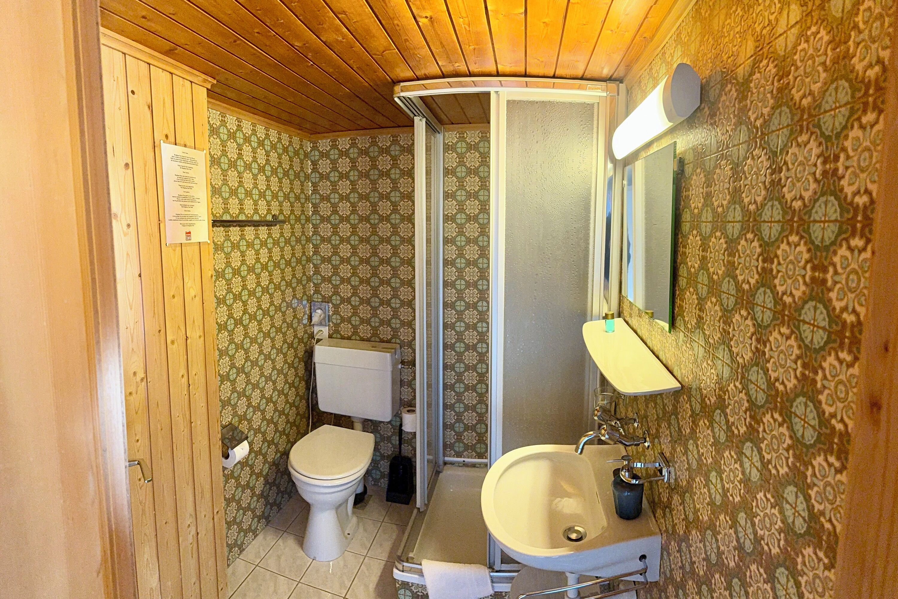 A compact bathroom with a toilet, sink, and shower.