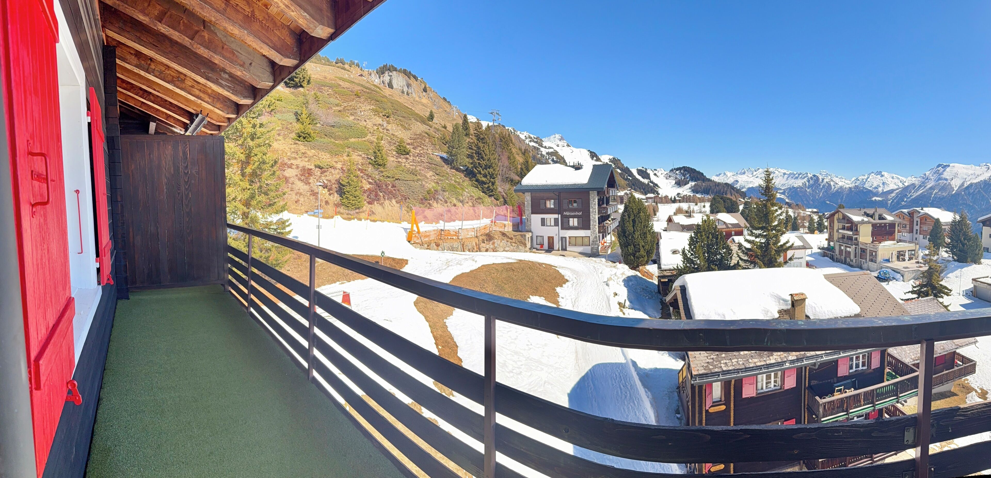 Un balcon donnant sur un village enneigé et des montagnes.