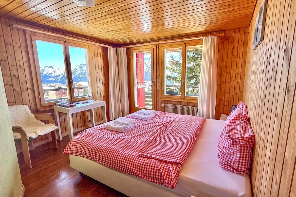 Una habitación de cabaña de madera con una cama, un escritorio y una silla.