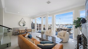 Ein geräumiges Wohnzimmer mit einer Ledersofa, einem Couchtisch und Blick auf einen Hafen durch große Fenster.