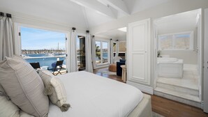 Ein geräumiges Schlafzimmer mit einem großen Bett, Meerblick und einem Badezimmer mit einer Marmortreppe.