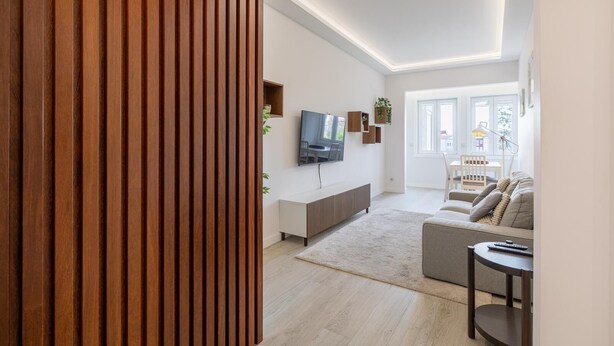 A modern living room with a TV, sofa, and a dining area.