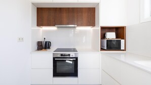 A modern kitchen with white cabinetry, a built-in oven, a coffee maker, and a microwave.