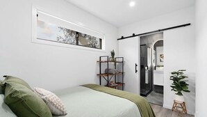 A bedroom with a bed, a sliding door, a small stool, and a potted plant. - Hollow Mountain Cabin Laharum Dadswell bridge halls gap (Laharum)