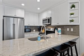A modern kitchen with white cabinetry, stainless steel appliances, a granite countertop, and a built-in sink.