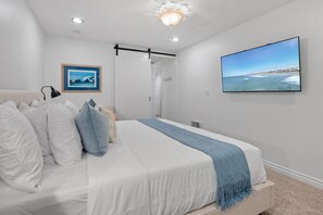 A bedroom with a bed, a wall-mounted TV, a framed picture, and a ceiling light. - New Listing: Beautiful Interior Unit – North Coast Village G207 (Oceanside)
