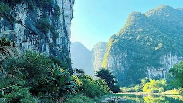 A serene river with lush greenery and rocky cliffs.