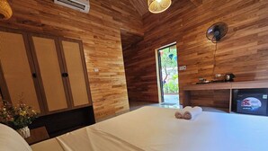 A wooden room with a bed, a desk, and a small window. - An Riverside Ecolodge (Tay Hoa Lu)