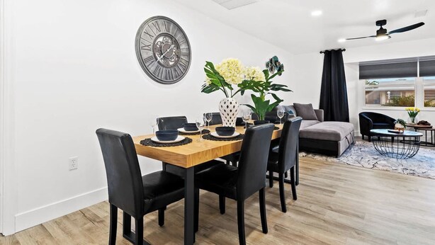 A dining area with a wooden table, black chairs, and a wall-mounted clock. - Venice Oasis | Pool, 3 King Beds, 2.5 miles >Beach (Venice)