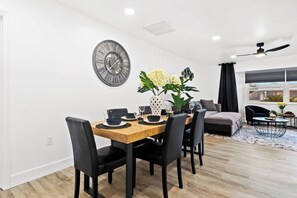 Un comedor con una mesa de madera, sillas negras y un reloj en la pared.