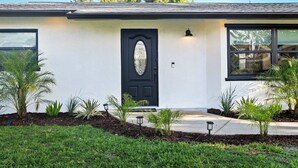 A single-story house with a black front door, a small porch, and a window on the right side. - Venice Oasis | Pool, 3 King Beds, 2.5 miles >Beach (Venice)