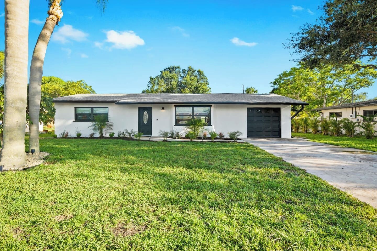 A modern two-story house with a flat roof, a front garage, and a well-maintained lawn.