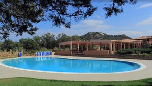 A swimming pool with lounge chairs and a covered patio area. - Exclusive 2 Separate Flats Residence Bouganville (Olbia)