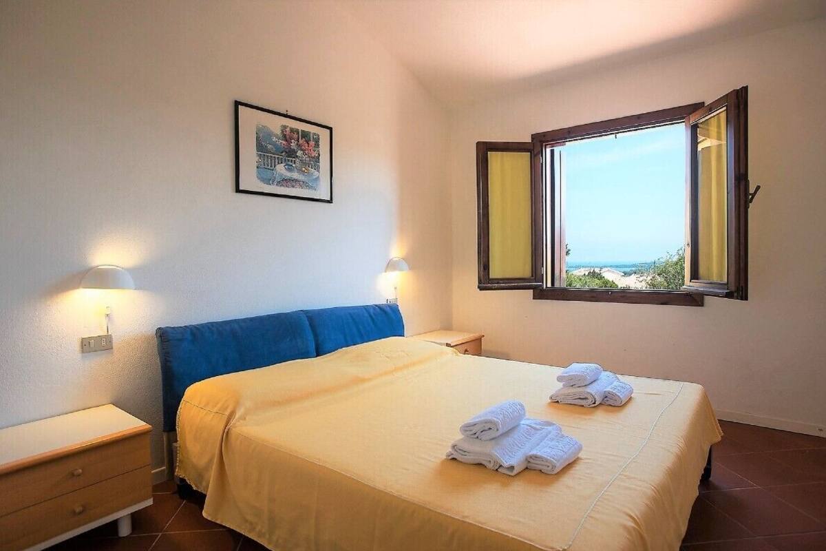 Habitación de hotel con una cama, una mesita de noche, una ventana con vistas y un cuadro colgado en la pared.
