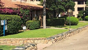 A residential area with stone walls, a well-maintained lawn, and a clear sky. - Exclusive 2 Separate Flats Residence Bouganville (Olbia)