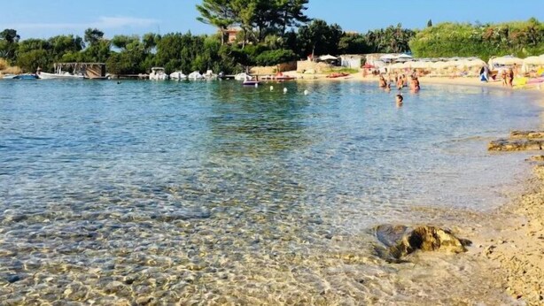A clear beach with boats, umbrellas, and people swimming. - Exclusive 2 Separate Flats Residence Bouganville (Olbia)
