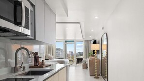 Une cuisine moderne dotée d’un grand îlot central, d’un four encastré et offrant une vue sur la ville grâce à de grandes fenêtres.