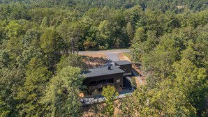 A modern house surrounded by dense forest with a clear view of distant mountains. - New Lake House on Lake Adger near TIEC, Vineyards, Orchards, Biltmore and more (Mill Spring)