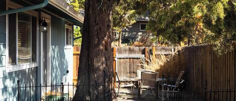A residential backyard with a large tree, a wooden fence, and outdoor furniture.