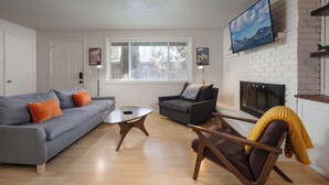 A living room with a gray sofa, a wooden coffee table, a brown armchair, and a fireplace. - 10min to Downtown Bend Chic 2bdr (Bend)