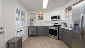 A modern kitchen with white cabinets, stainless steel appliances, and a tiled floor. - 10min to Downtown Bend Chic 2bdr (Bend)