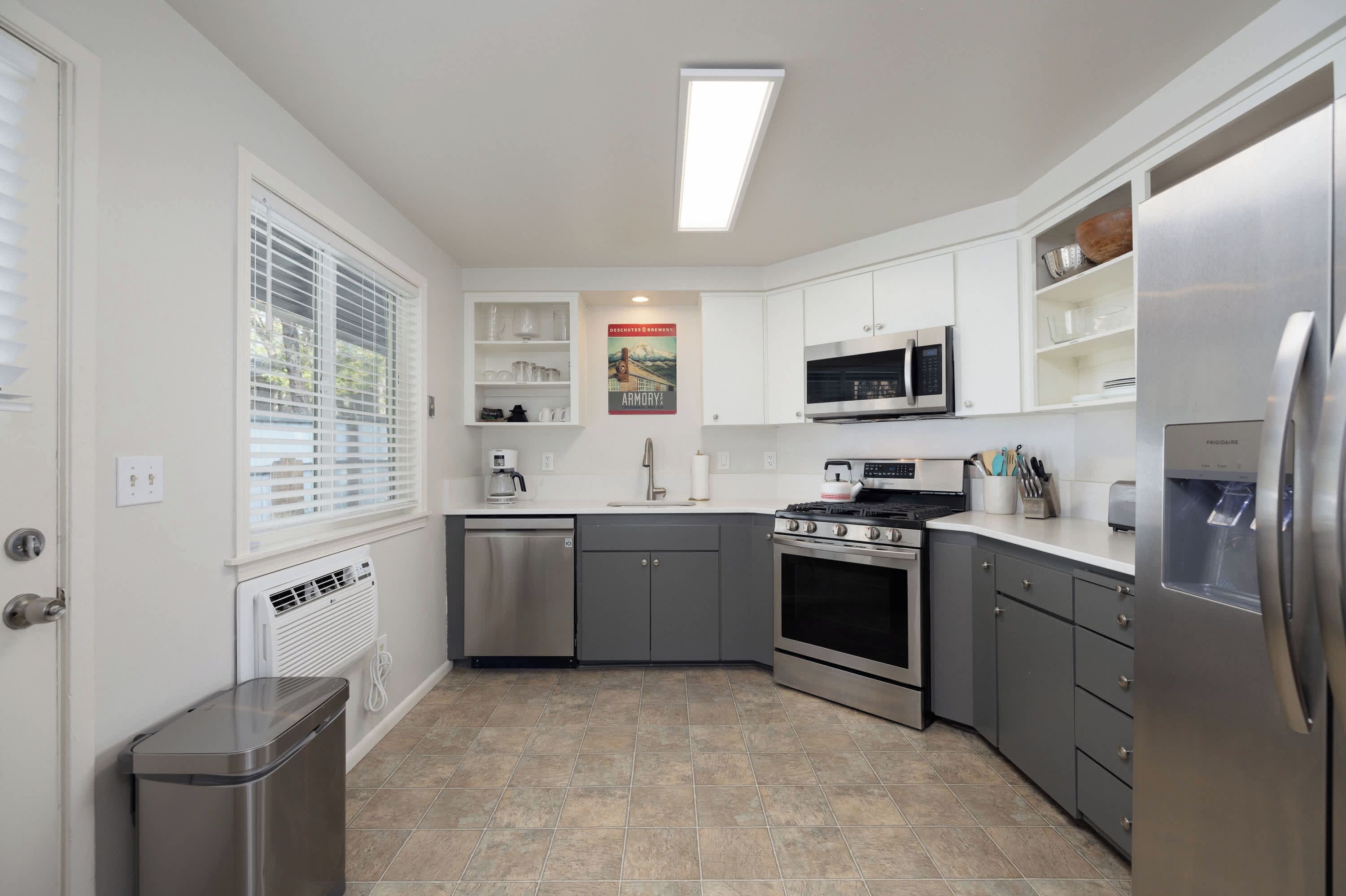 A modern kitchen with white cabinets, stainless steel appliances, and a tiled floor.