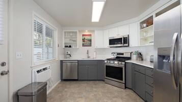 A modern kitchen with white cabinets, stainless steel appliances, and a tiled floor.