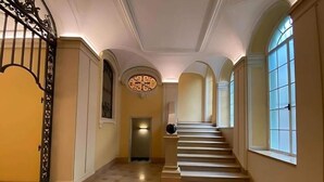 A grand hallway with a staircase, ornate metal railings, and large windows. - Palazzo Lomellini Historic Retreat (Genova)