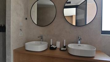 Un baño moderno con dos espejos redondos, un mueble de tocador de madera y un lavabo blanco.