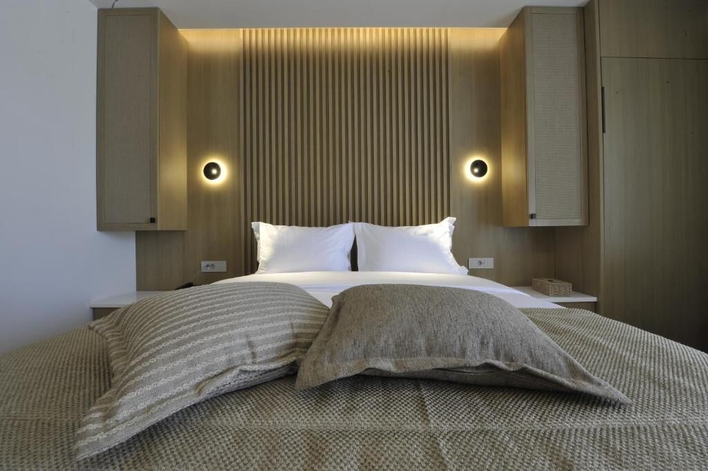 Un dormitorio moderno con una cama grande, dos mesitas de noche y cabeceros de madera empotrados con iluminación integrada.