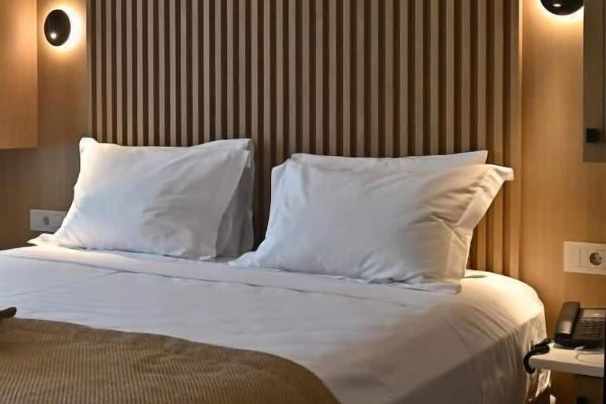 Una habitación de hotel con una cama grande, paneles de madera en las paredes y un teléfono en la mesita de noche.