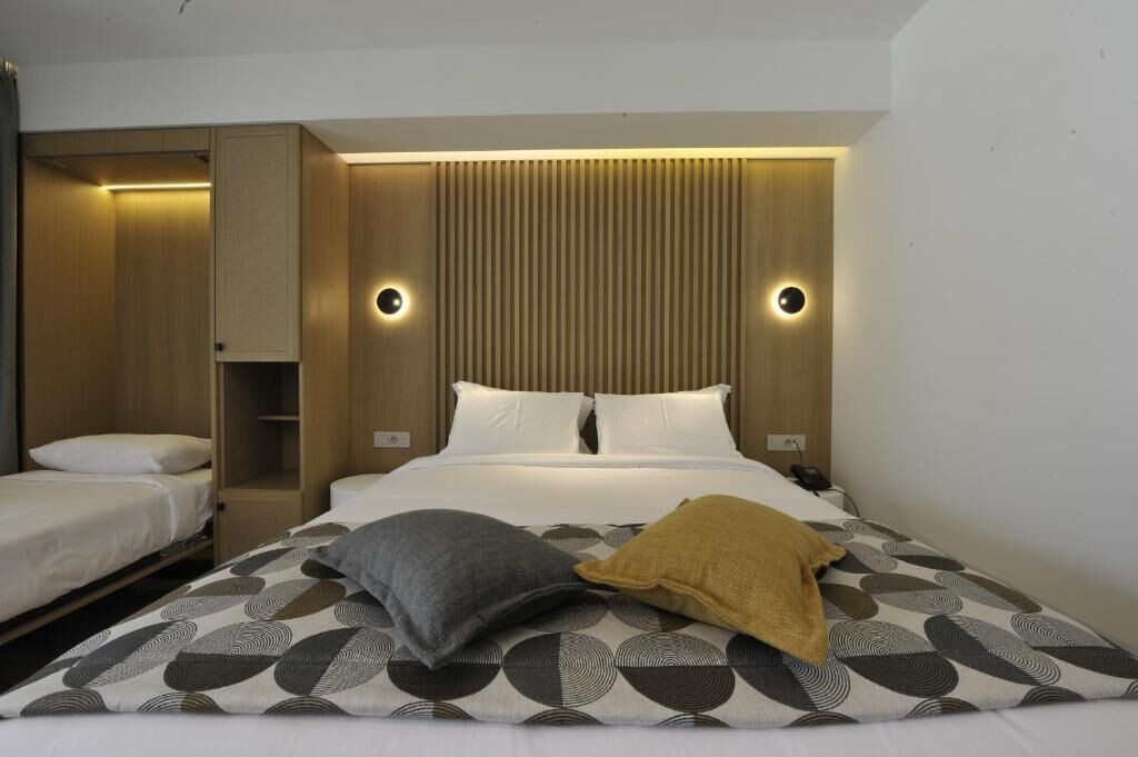 A hotel room with a bed, a bedside table, a wardrobe, and a mirror.