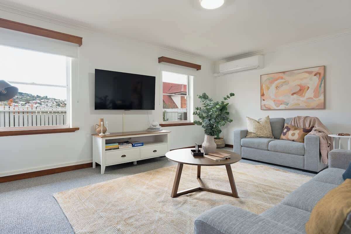 Una sala de estar con televisor, sofá, mesa de centro y una planta.