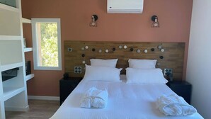 A neatly made bed with white linens and towels, a wooden headboard with circular decorations, and a window with a view of greenery. - Villa Ghjuvan (Peri)
