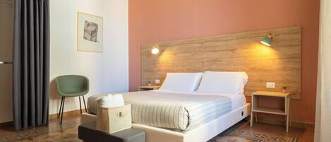 Una camera da letto con un letto, una sedia verde, un tavolino e un comodino.