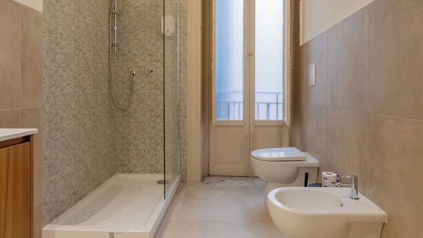 Une salle de bain moderne dotée d’une douche à parois de verre, de toilettes et d’un bidet.
