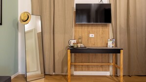 A room with a wooden floor, a black table with a kettle and a mug, a mirror, and a TV mounted on the wall. - EXPA  (Palermo)