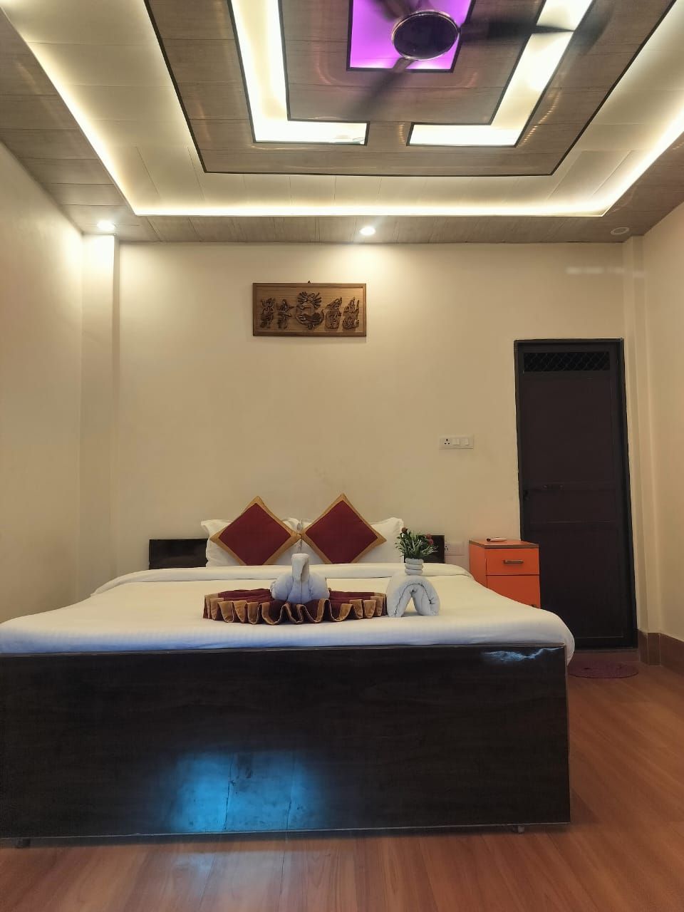 A modern bedroom with a large bed, a ceiling light fixture, and a door.