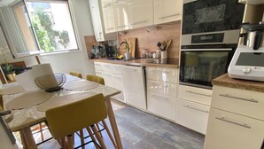 Una cocina moderna con armarios blancos, una mesa de comedor con sillas amarillas y suelo de madera.