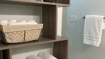 Un baño con estantes de madera que sostienen toallas y plantas en macetas.